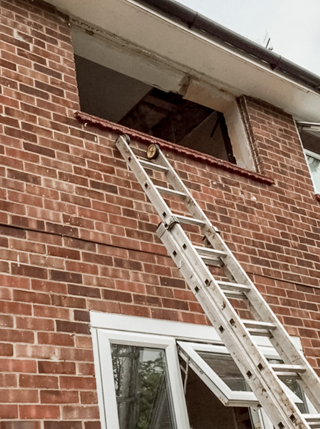 top floor window with ladder leaning up against it