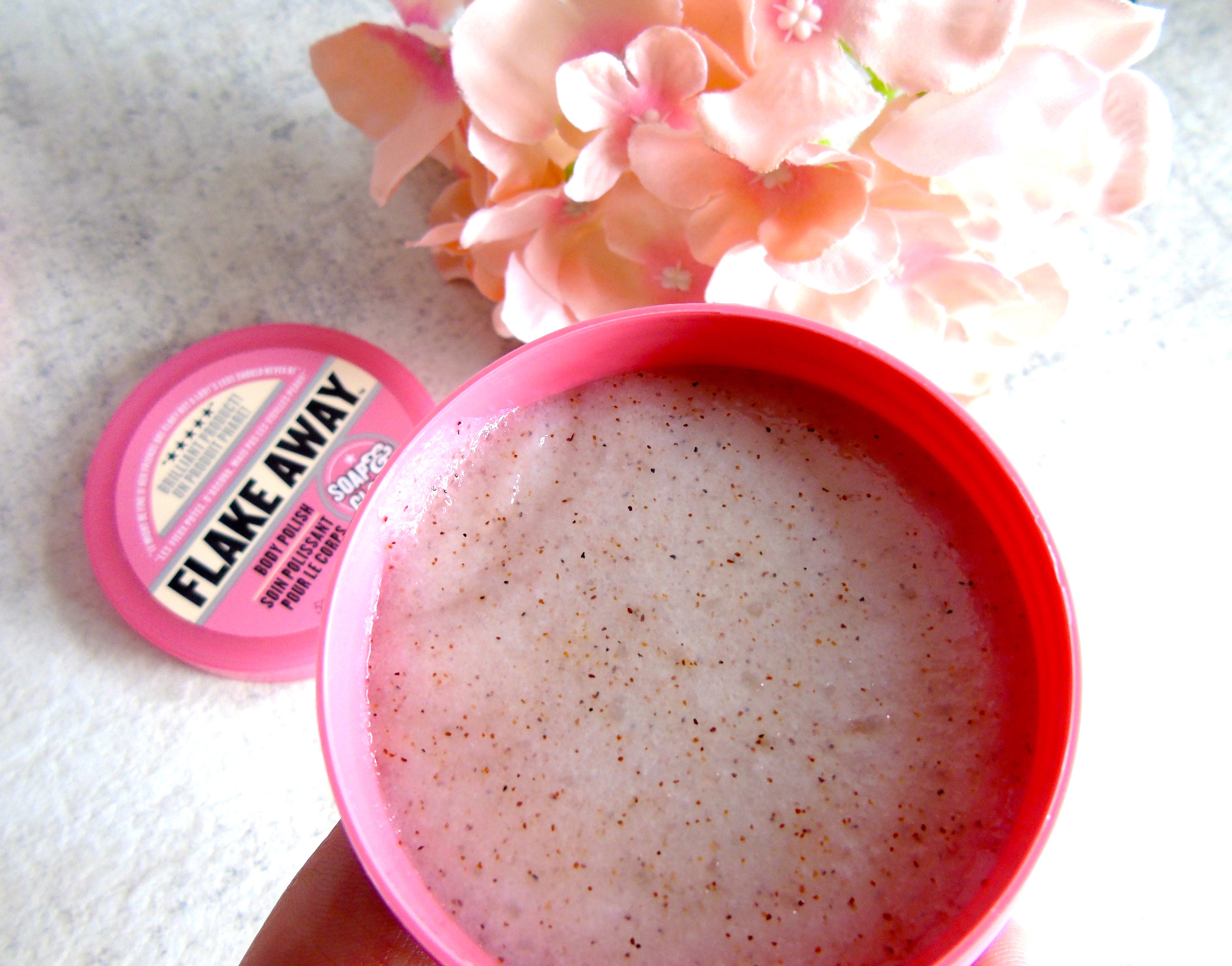 a close up view of a tub of grainy body scrub liquid by soap and glory 