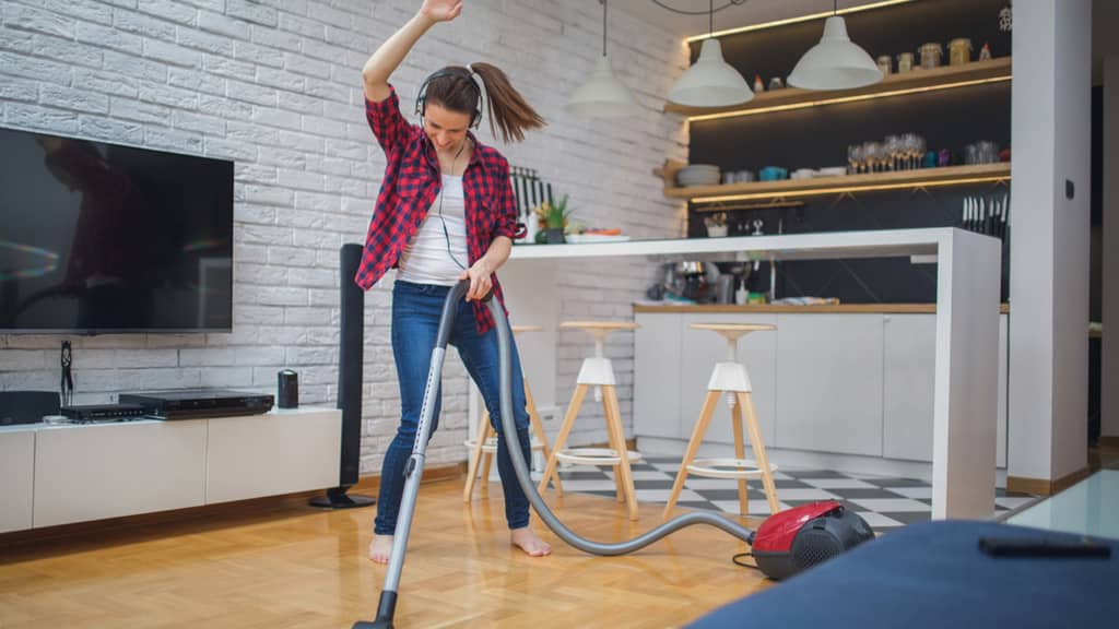 a lady dancing with a vacuum cleaning while doing a spring clean