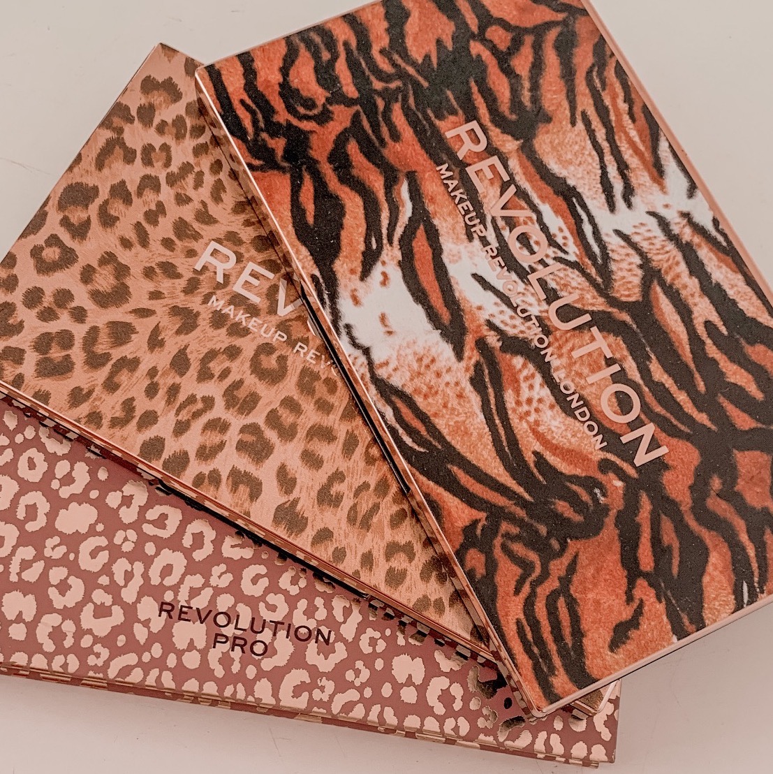 3 patterned revolution beauty eyeshadow palettes stacked on top of each other in a fan effect