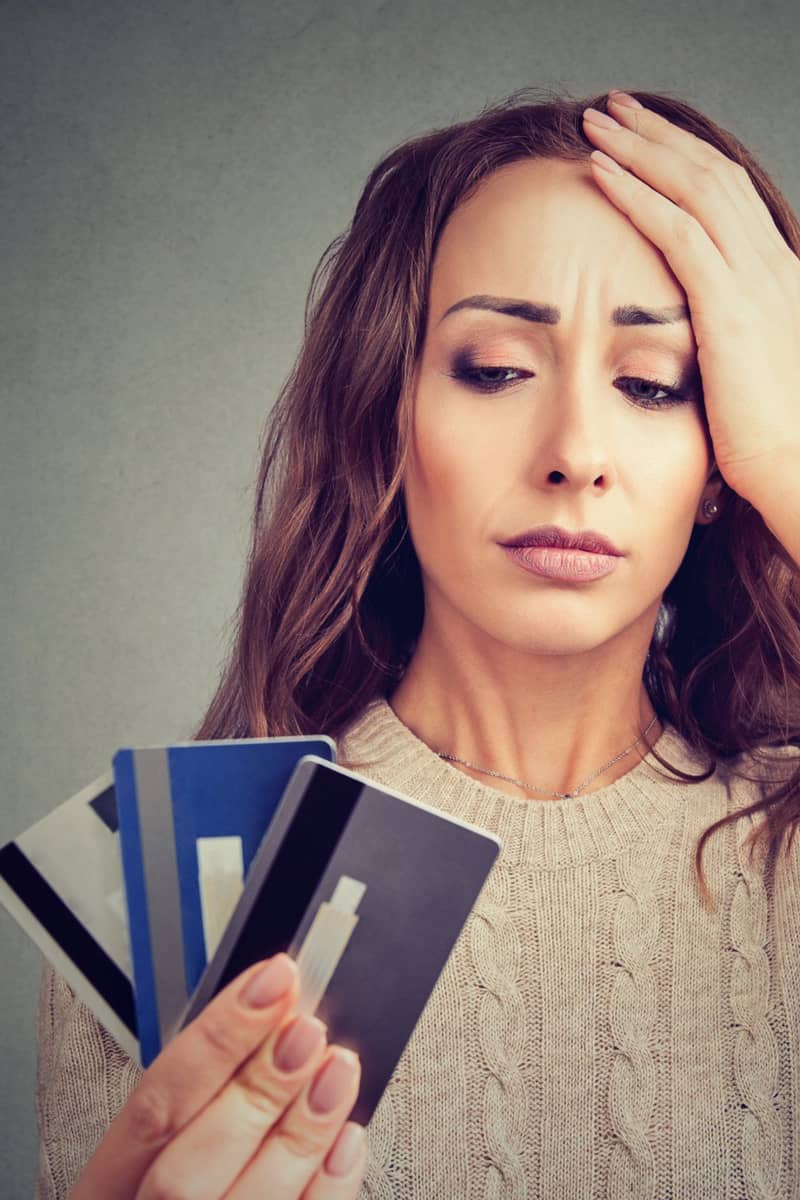 a lady looking worried holding up credit cards assessing here debts