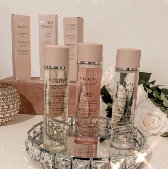 a trio of skincare products in see through bottles with pink lids displayed in a row
