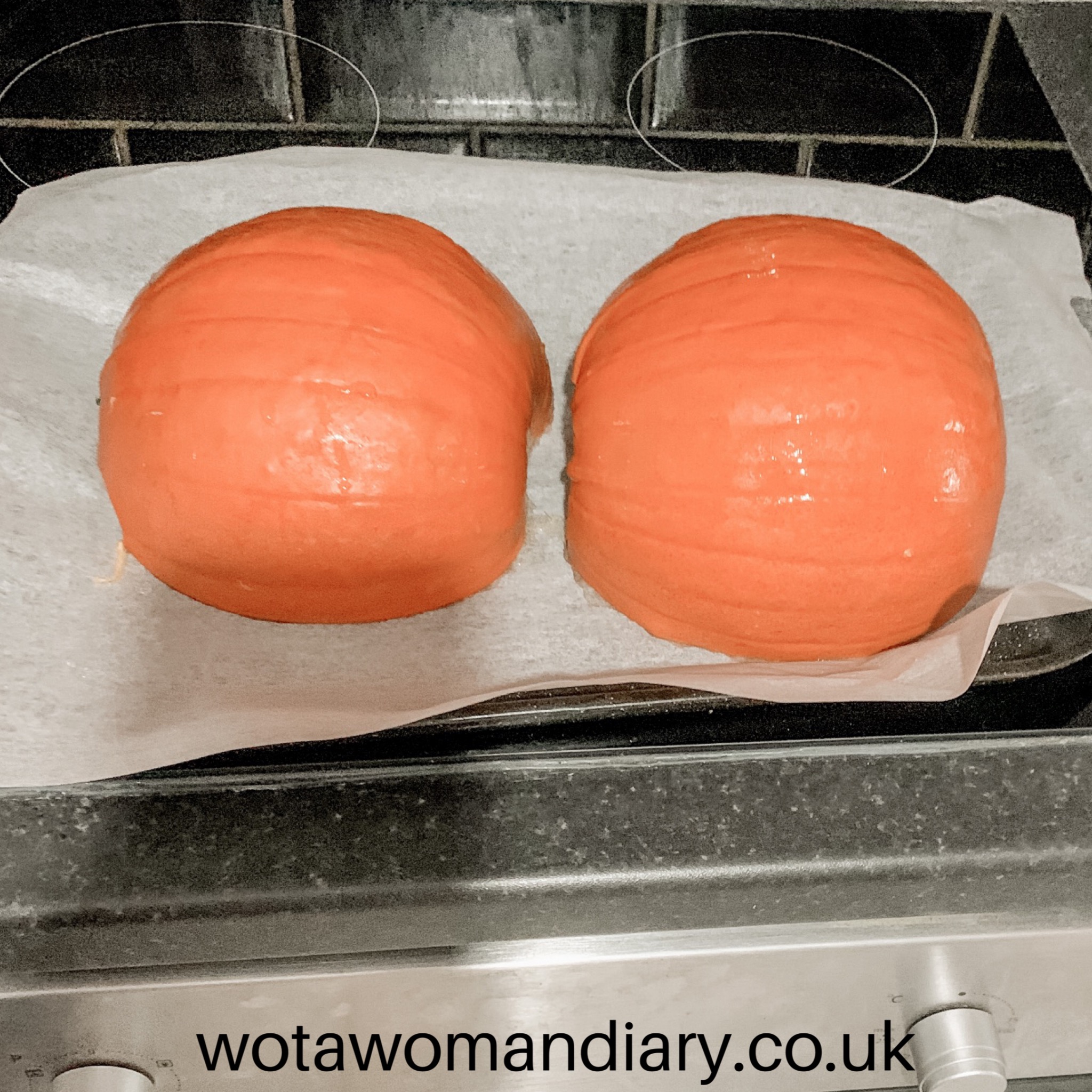 a pumpkin cut in half face down on a baking tray ready to bake