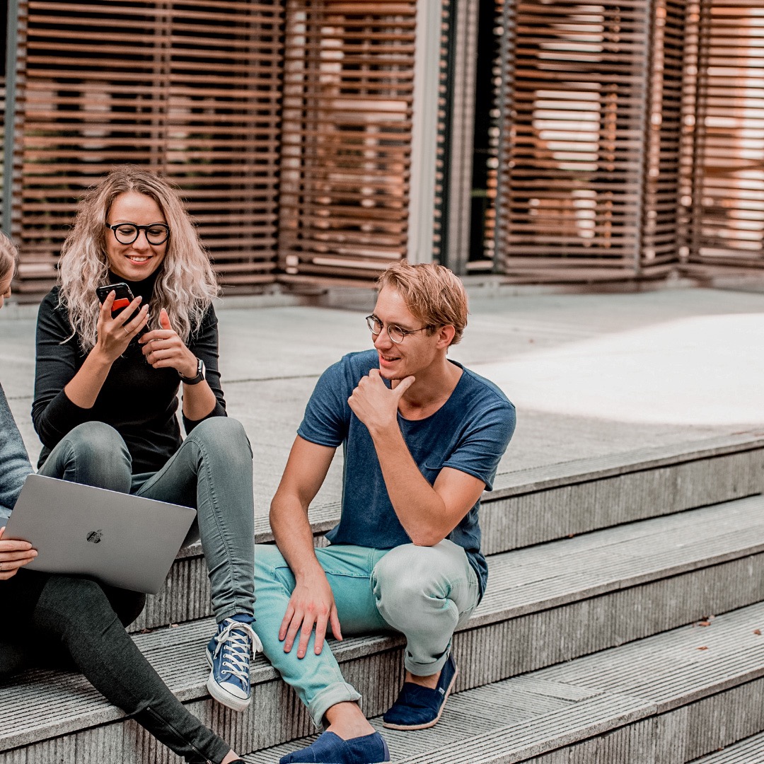 students sitting oon steps outside of university