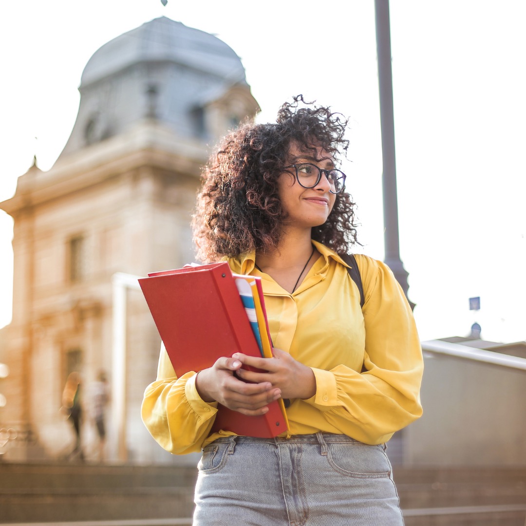 a intelligent looking university study standing smiling holding her folders