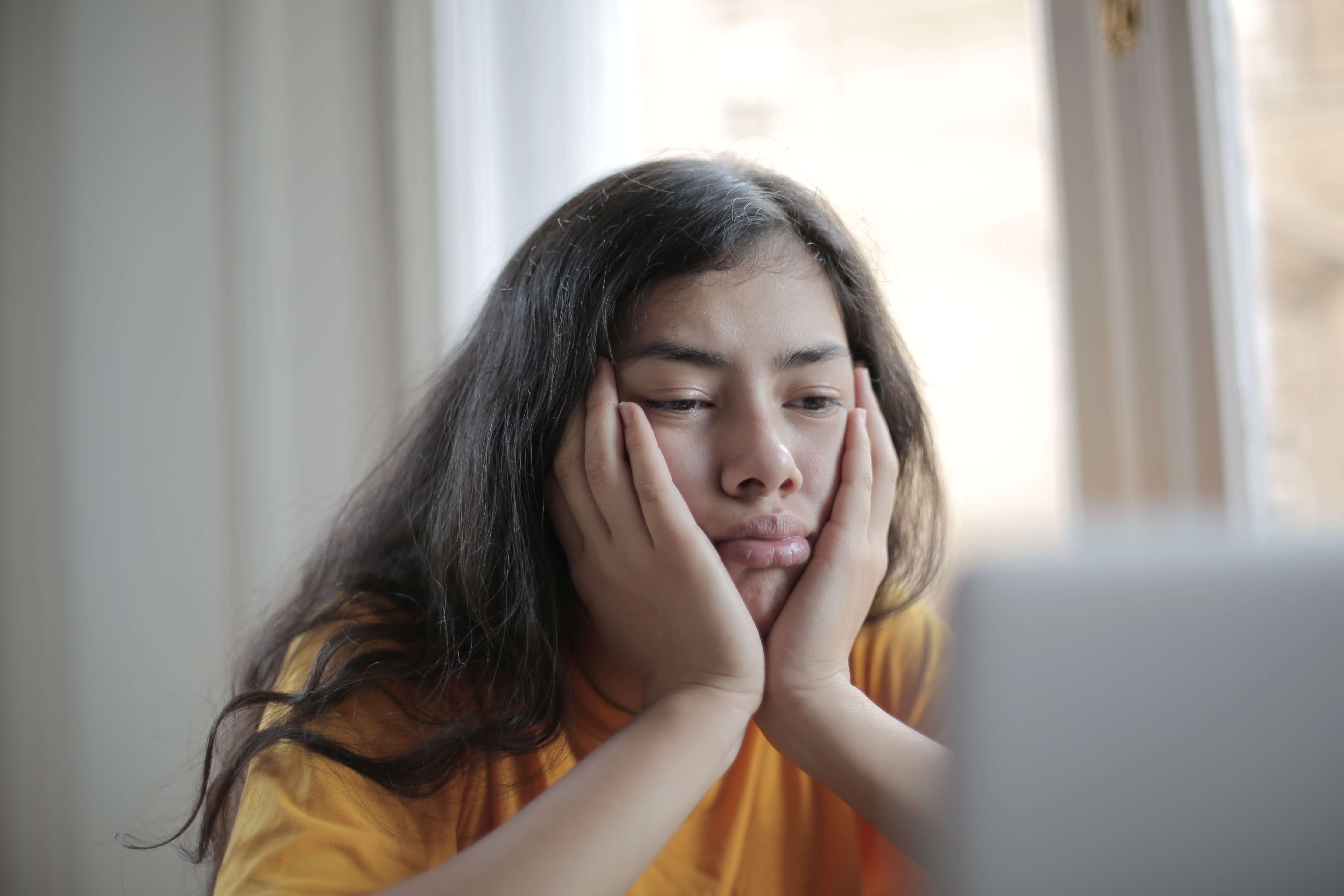 a lady sitting with her face in her hands looking bored with nothing to do
