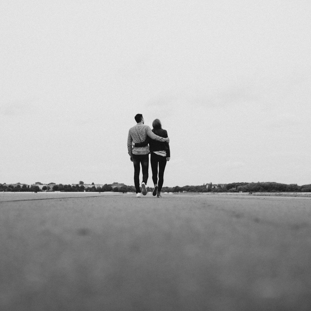 a couple with their arm round each other walking away from the camera