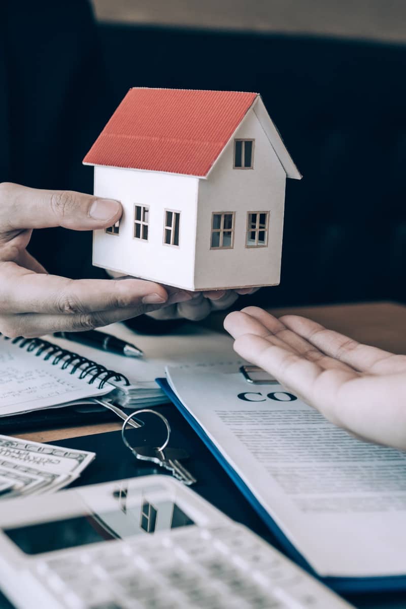 a house image being passed between 2 people to secure their future