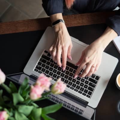 a ladies hands perched over a laptop writing a blog