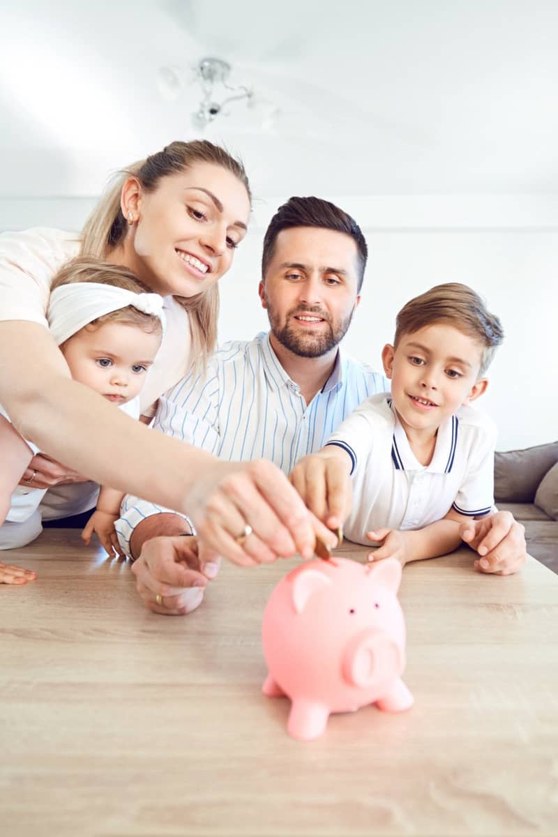 a family around a piggy bank saving their money