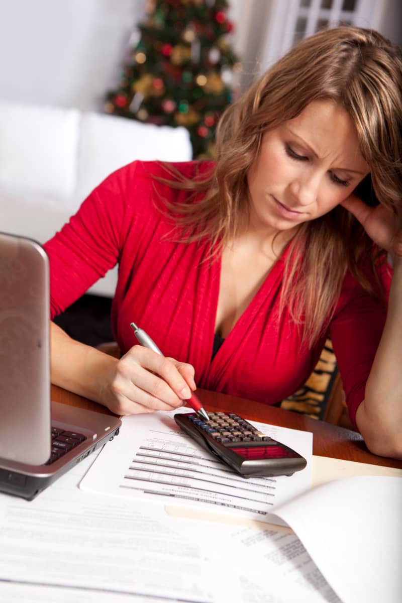 a lady sitting with a calculator working out how to pay off her debts