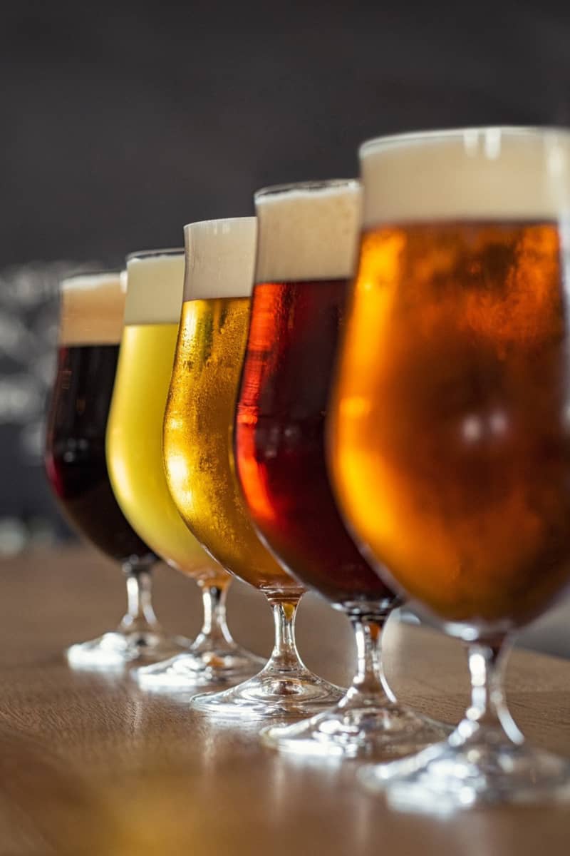 a line of glasses with different types of beer in them