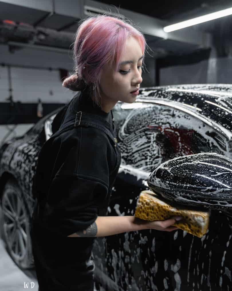 a lady cleaning the outside of a car